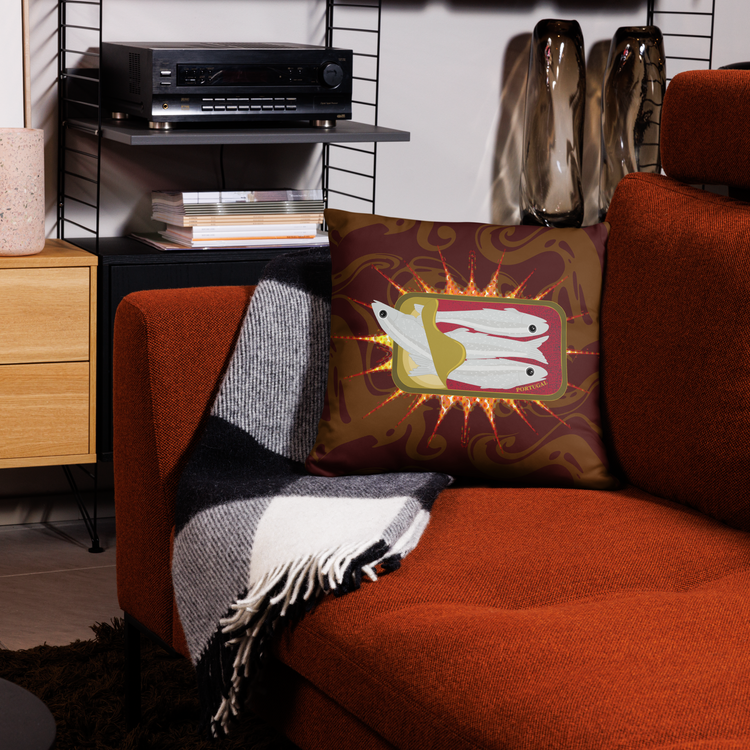 Decorative pillow featuring a sardine can design on a patterned background, placed on an orange sofa.