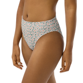 Woman wearing high-waisted bikini bottom with floral pattern in pink and green on white background.