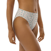 White high-waisted bikini bottom with pink floral pattern on a model.