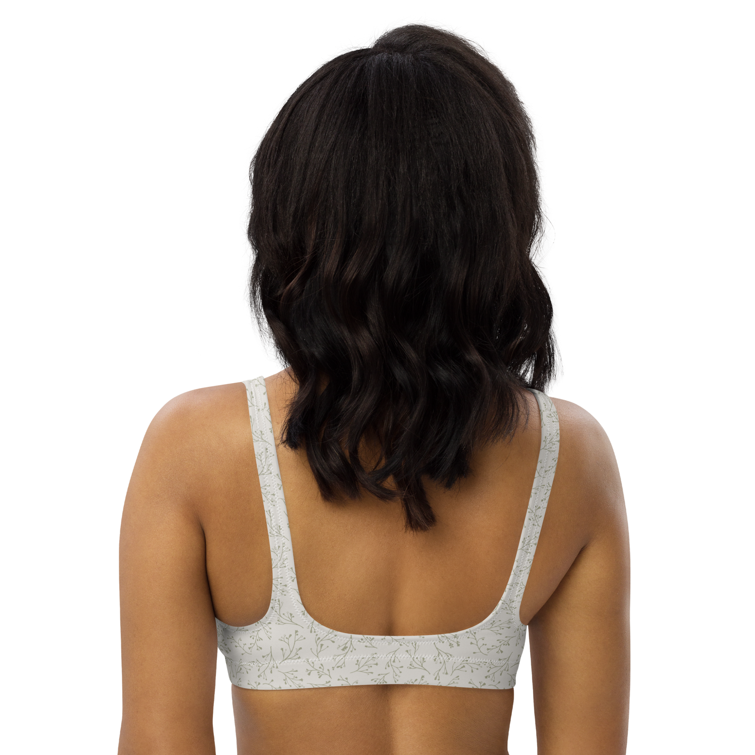 Woman wearing a white floral-patterned sports bra from the back.