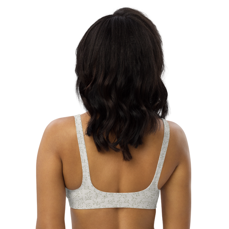 Woman wearing a white floral-patterned sports bra from the back.