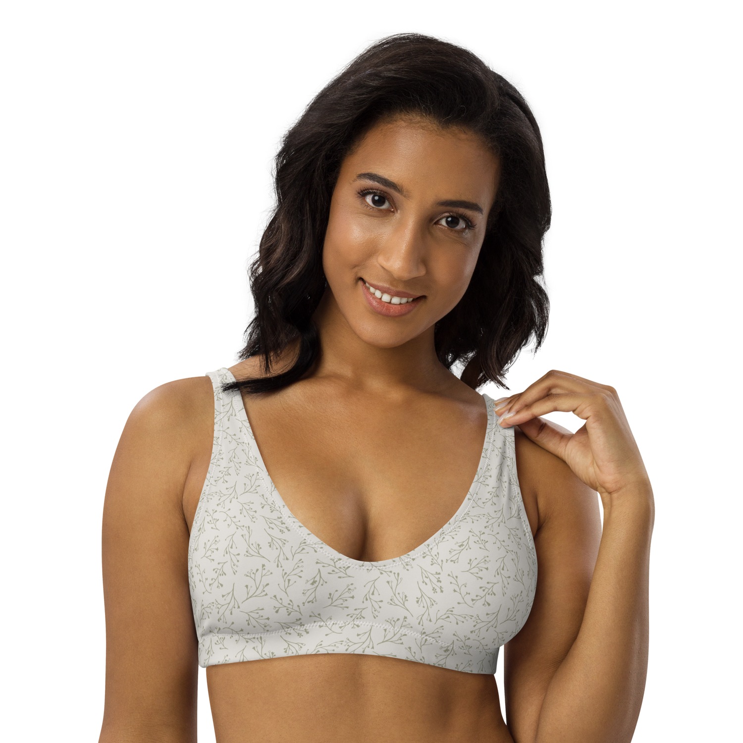 Woman wearing a white sports bra with green floral pattern.
