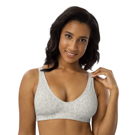 Woman wearing a white sports bra with green floral pattern.