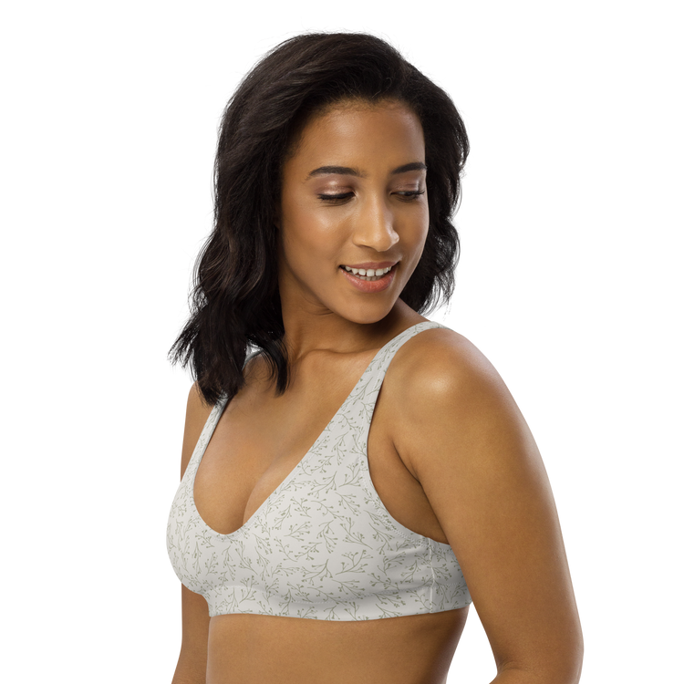 Woman wearing a white sports bra with a delicate green leaf pattern.