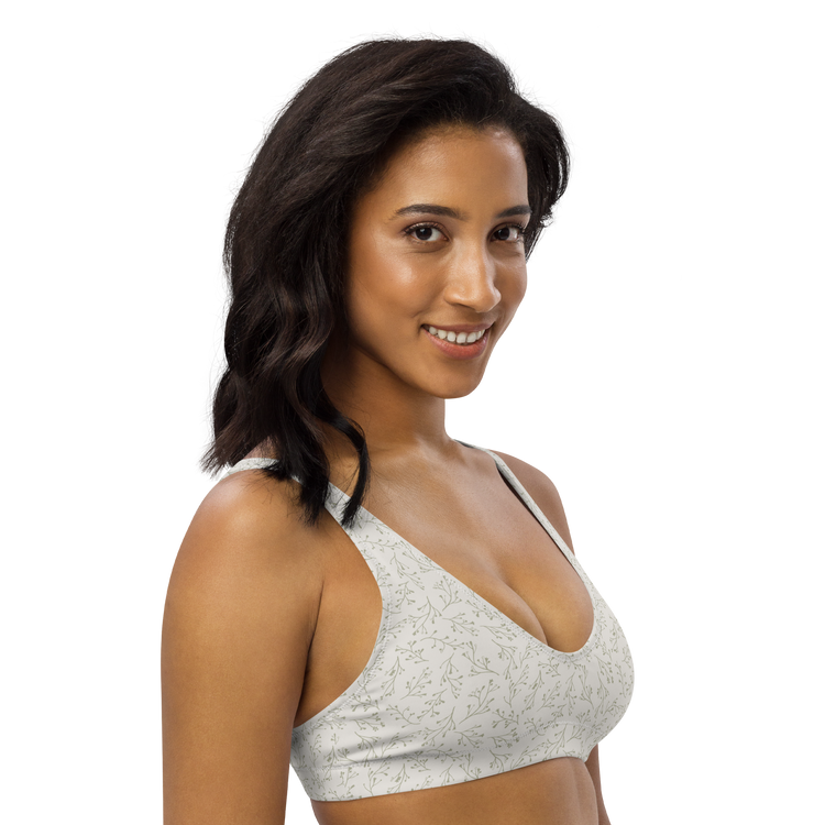 Woman wearing a white sports bra with a delicate green leaf pattern.